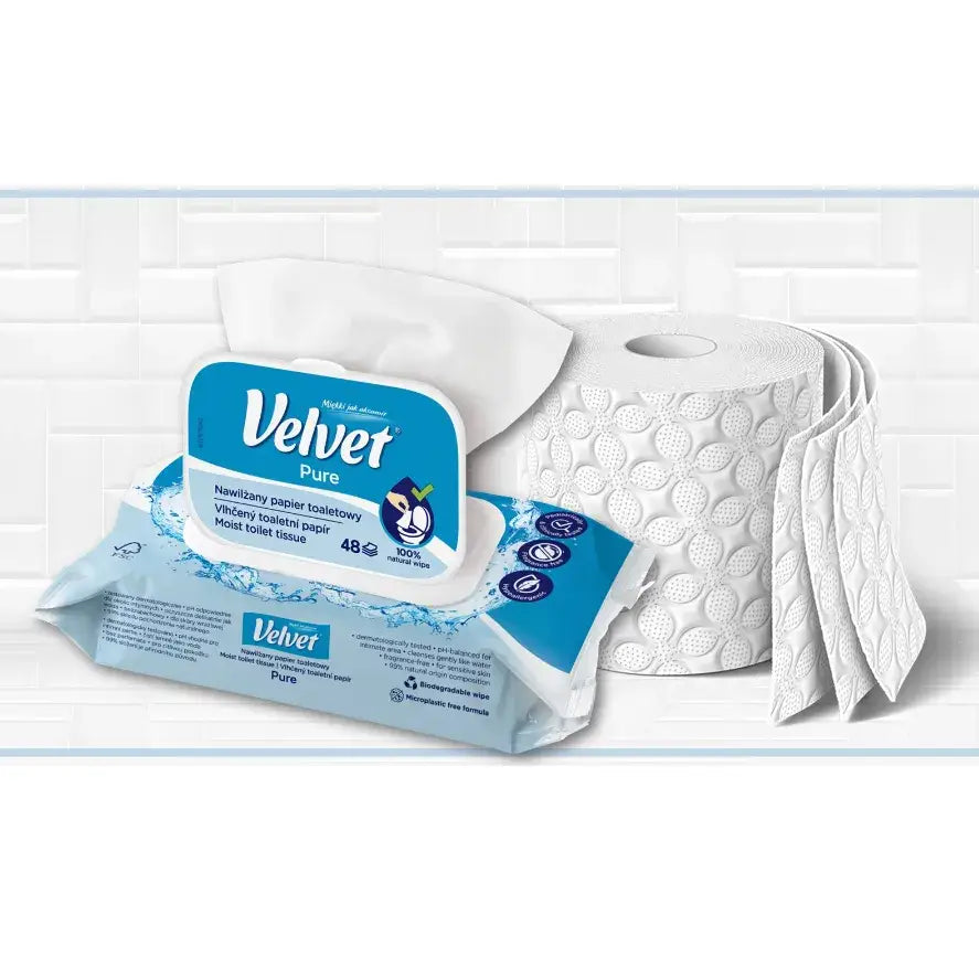 Fløyelsmykt våt toalettpapir Pure i blå og hvit pakke foran mønstret toalettrull, sett fra skrå vinkel.