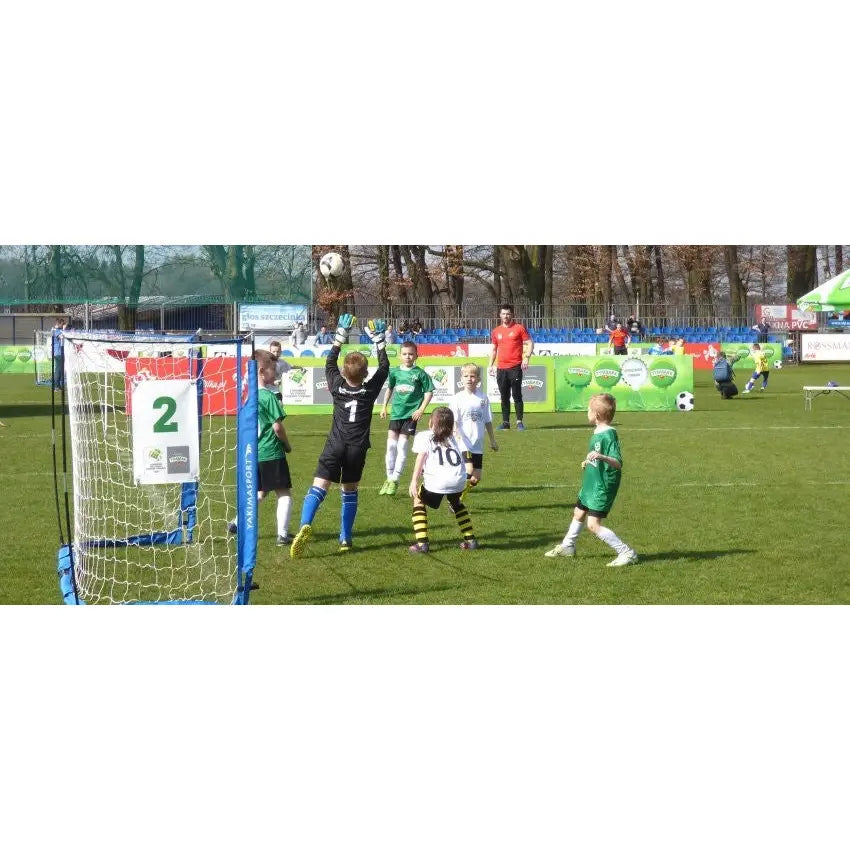 Foldbart blått fotballmål UNI ŻAK 3m, barn spiller fotball ute, keeper i svart drakt redder ballen.