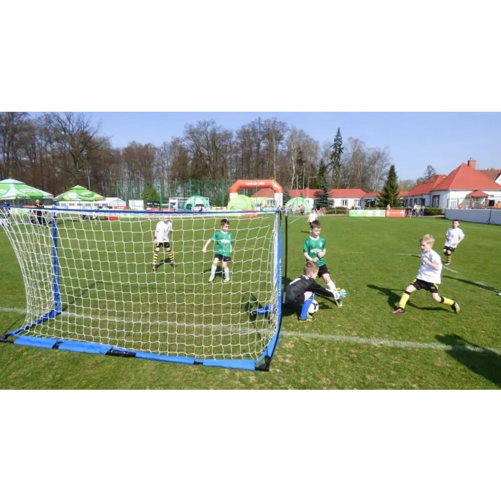 Foldbart fotballmål UNI ŻAK 3m, bakfra med barn i kamp og keeper som stopper ballen på gressbane.