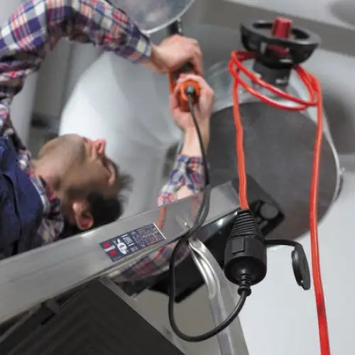 Forsterket skjøteledning 10m rød, brukt rundt rør mens en mann monterer ventil med oransje skrutrekker.