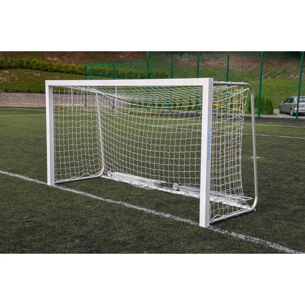 Fotballmål i hvitlakkert metall med hvitt nett, skrå forfra på kunstgress, viser robuste hjørner.