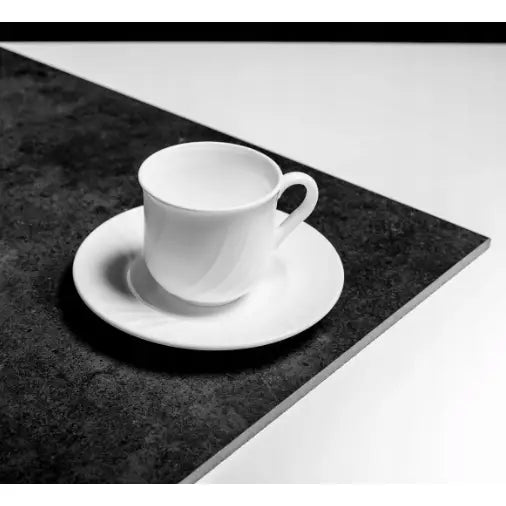 Hvit porselenskopp med tilhørende skål fra Bormioli Rocco, fotografert skrått ovenfra på mørkt bord.