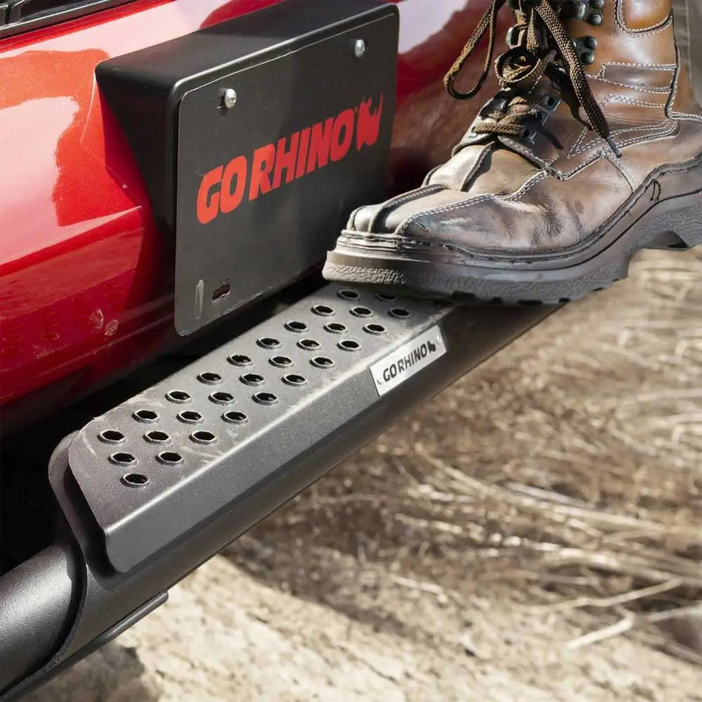 Frontbøyle med sort metalltrinn og grep, montert på rød Dodge RAM 1500 med skinnstøvel på trinnet.