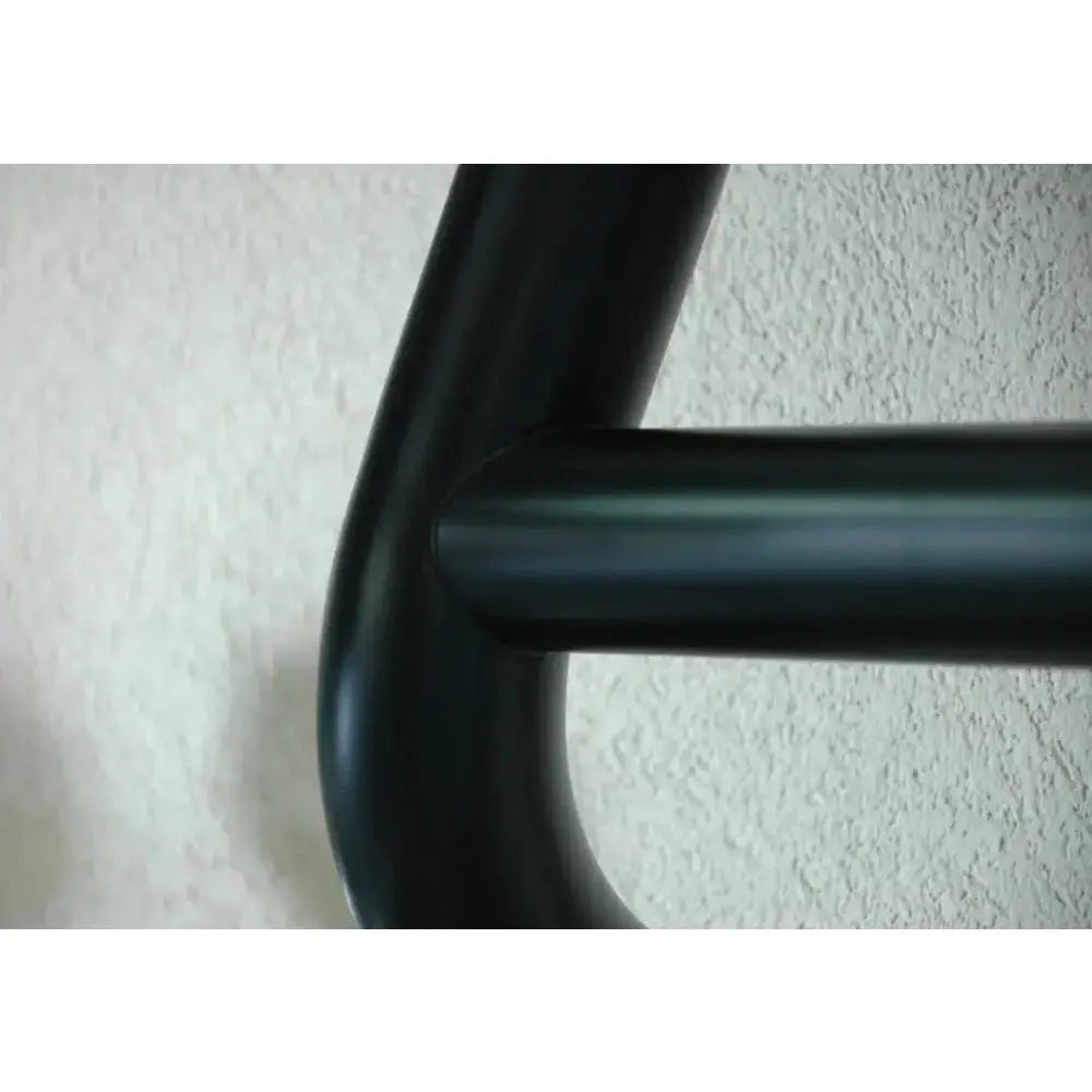 Kufanger Mitsubishi Outlander 18- i sort metall med synlig skjøt, nærbilde mot lys strukturert bakgrunn.