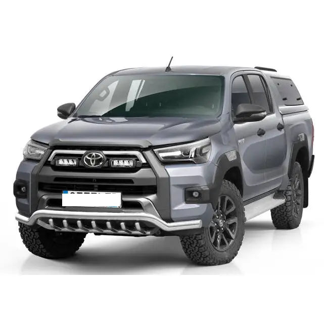 Frontbøyle Toyota Hilux Invincible med svarte detaljer, store terrengdekk og hardtop, sett skrått forfra.