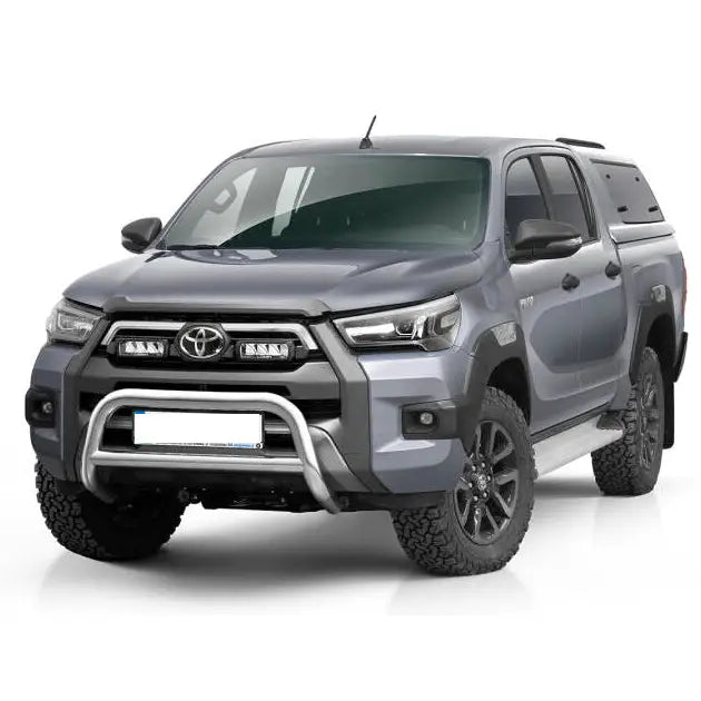 Frontbøyle Toyota Hilux Invincible 21 montert på grå pickup med doble lykter og store terrengdekk.