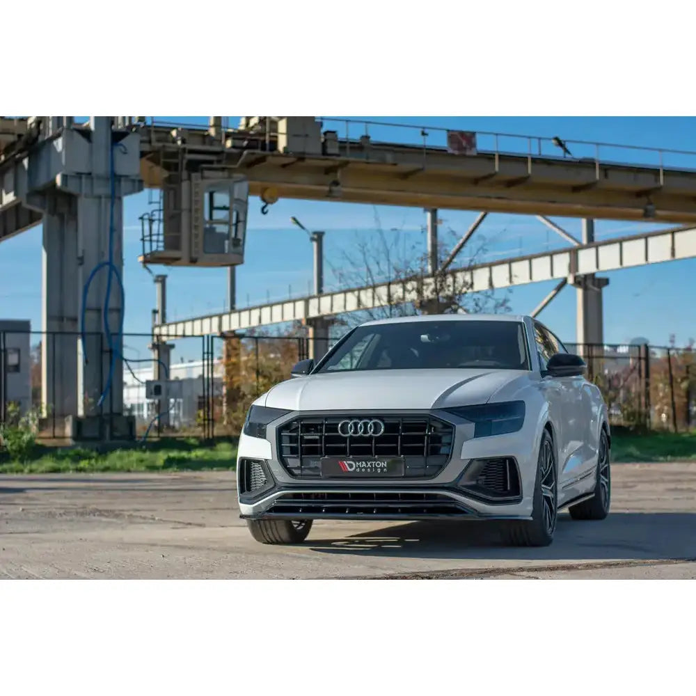 Frontleppe på Audi Q8 S-Line SUV sett forfra med sort grill, utendørs på industriområde.