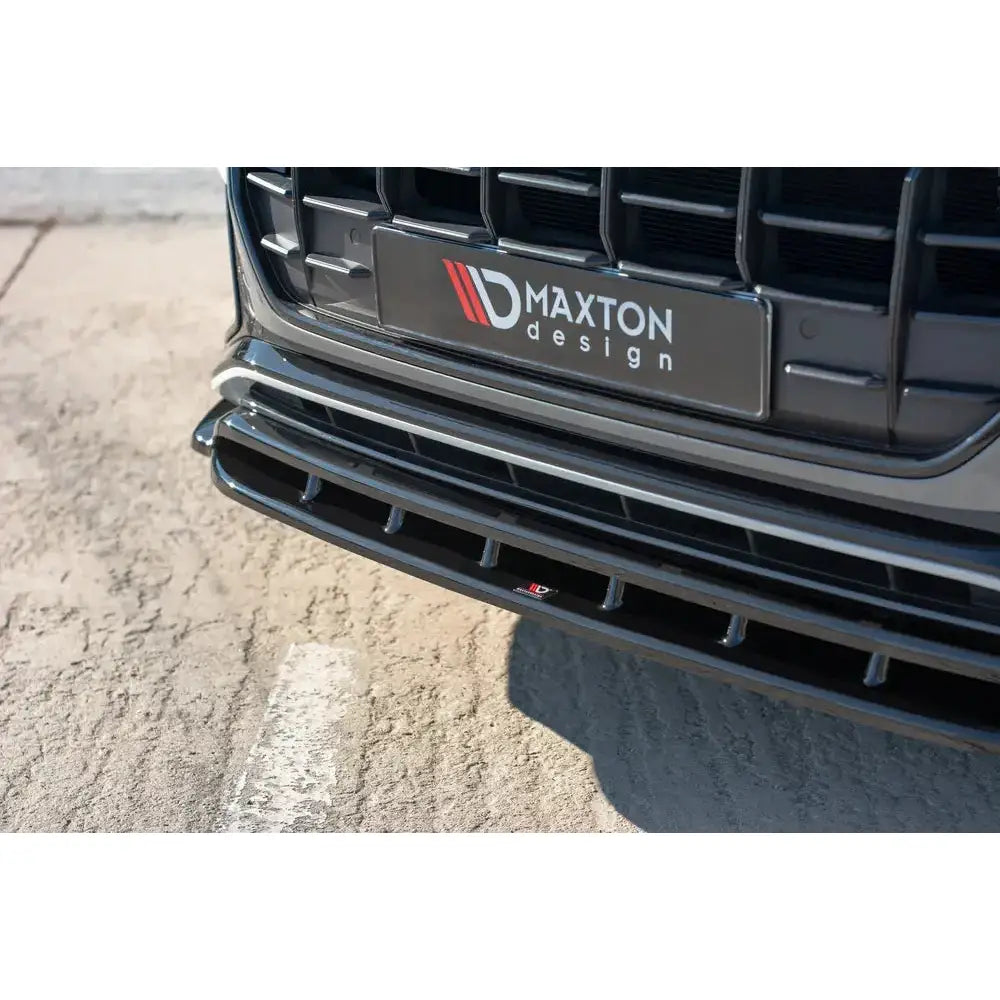 Front splitter Audi Q8 S-Line i sort blank finish med synlig logo og luftespalter, nærbilde mot asfalt.