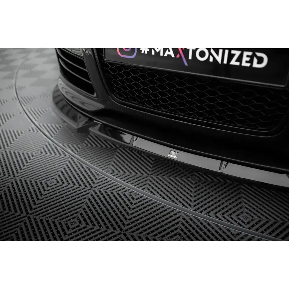 Spoiler Audi RS6 C6 V2 i sort blank finish, nærbilde nedenfra mot frontgrill med synlig logo.