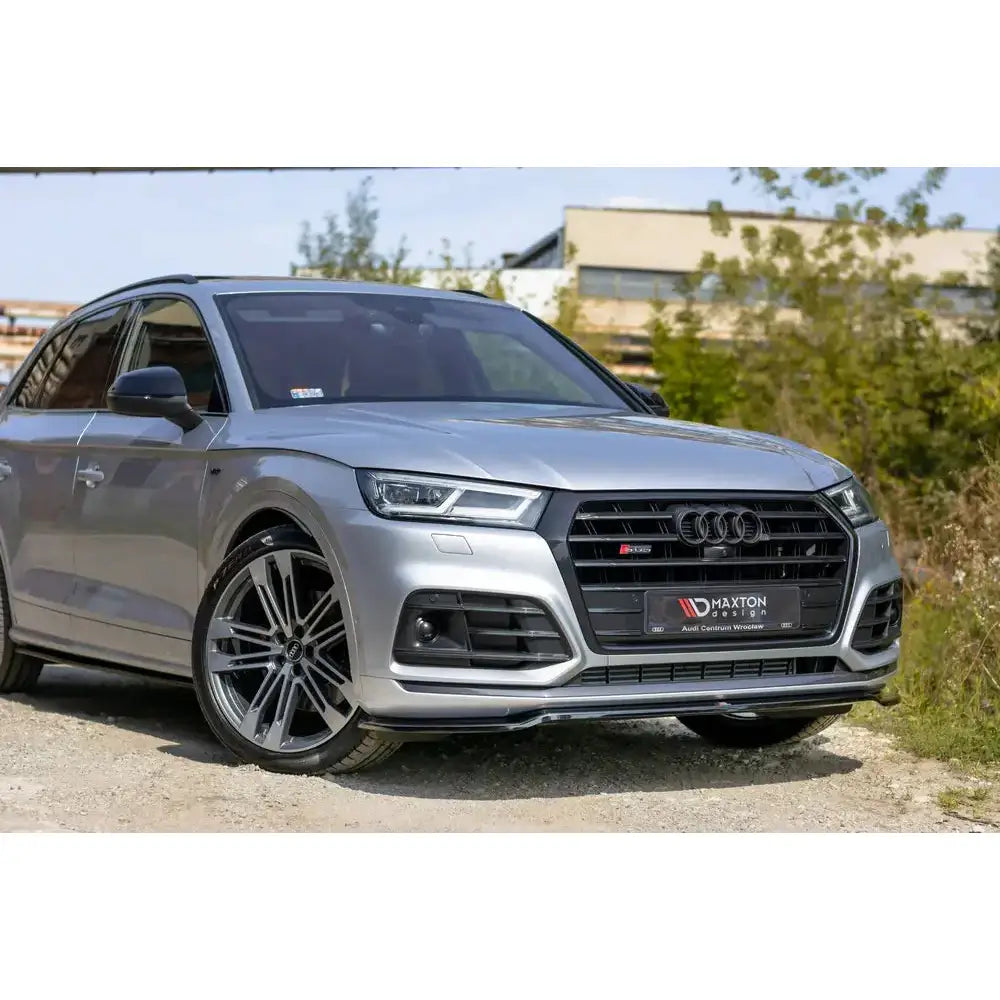 Frontleppe Audi SQ5 med store sorte felger og markant sort grill, parkert utendørs på grus.
