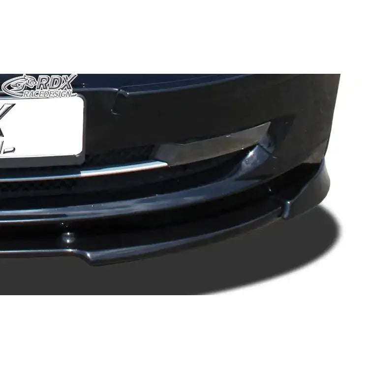 Front splitter til BMW 1 E81/E87, sort plast med blank finish, sett forfra med grill og skilt synlig.