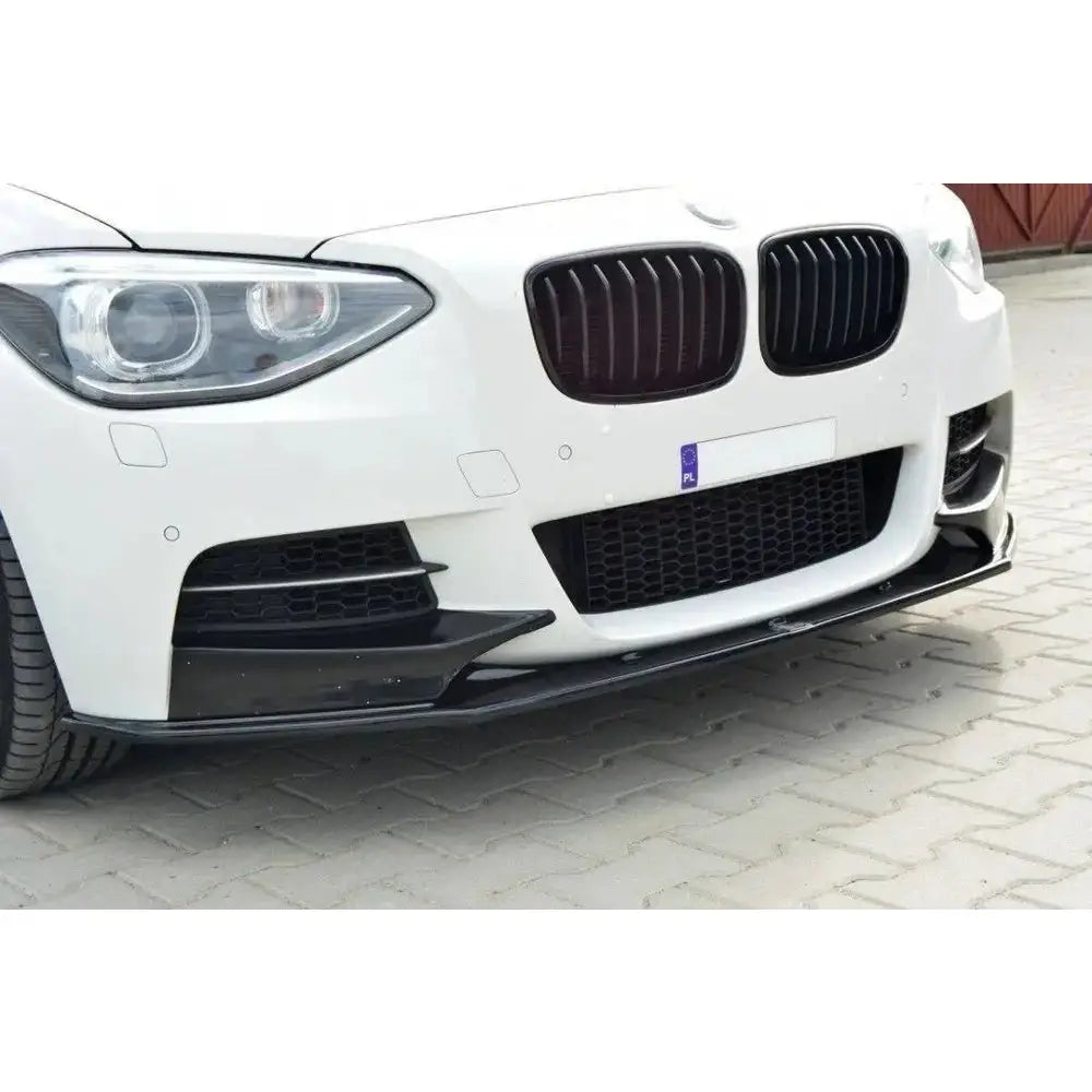 Front splitter for BMW 1 F20/F21 M-Power i sort blank plast montert på hvit bil, lav vinkel.