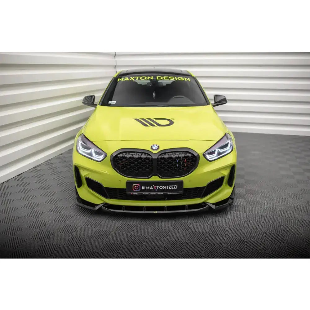 Frontspoiler på BMW 1 Serie F40 V.7 med sort grill og dekaler, sett forfra på gul sportsbil.