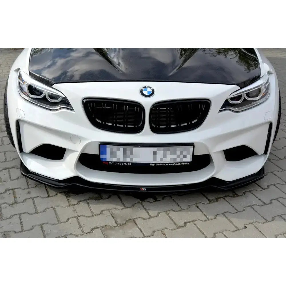 Spoiler på BMW M2 F87 Coupe med sort karbonfiberpanser og frontsplitter, sett rett forfra på brostein.