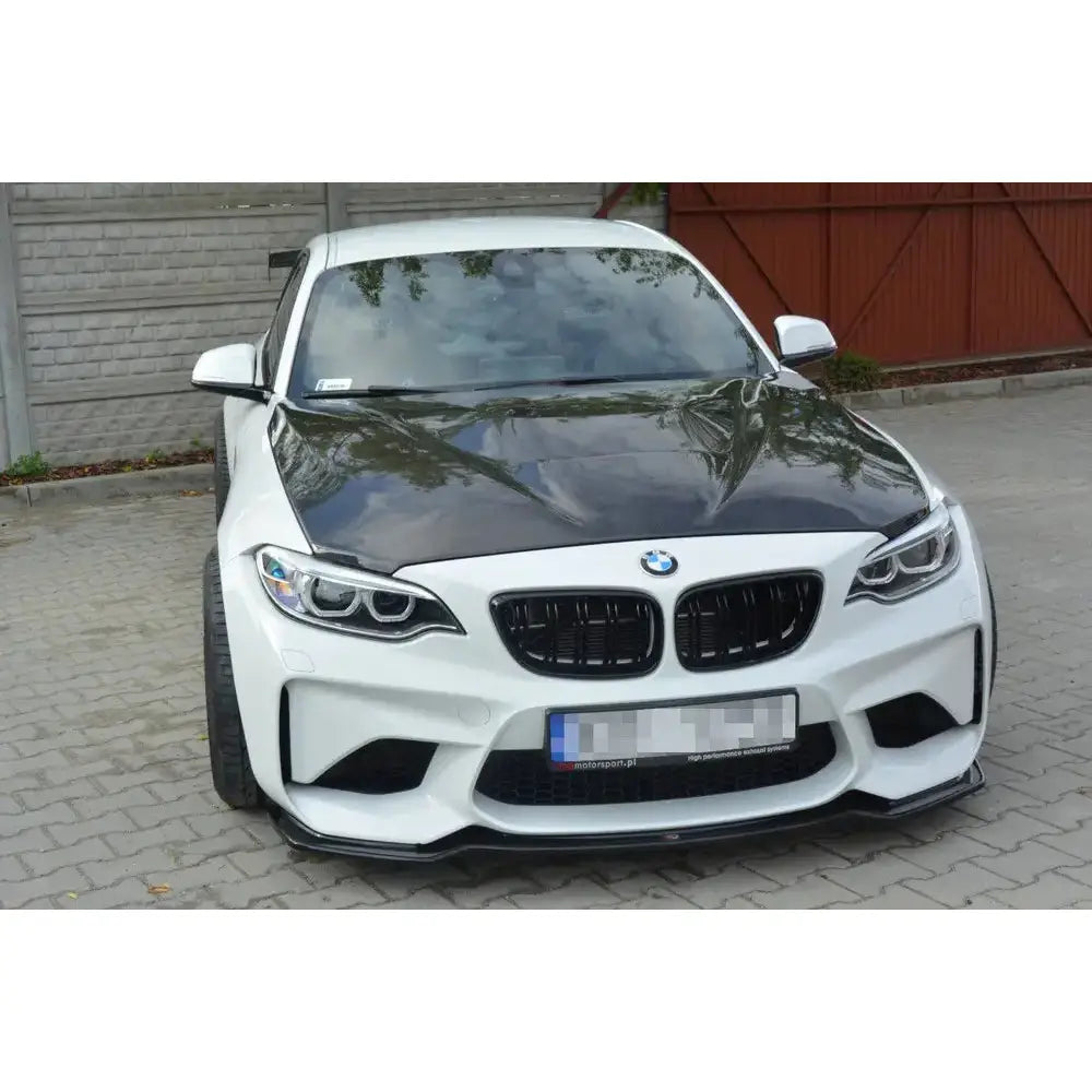 Front splitter på BMW M2 F87 Coupe med sort karbonpanser og svarte grilldetaljer, parkert på brostein.