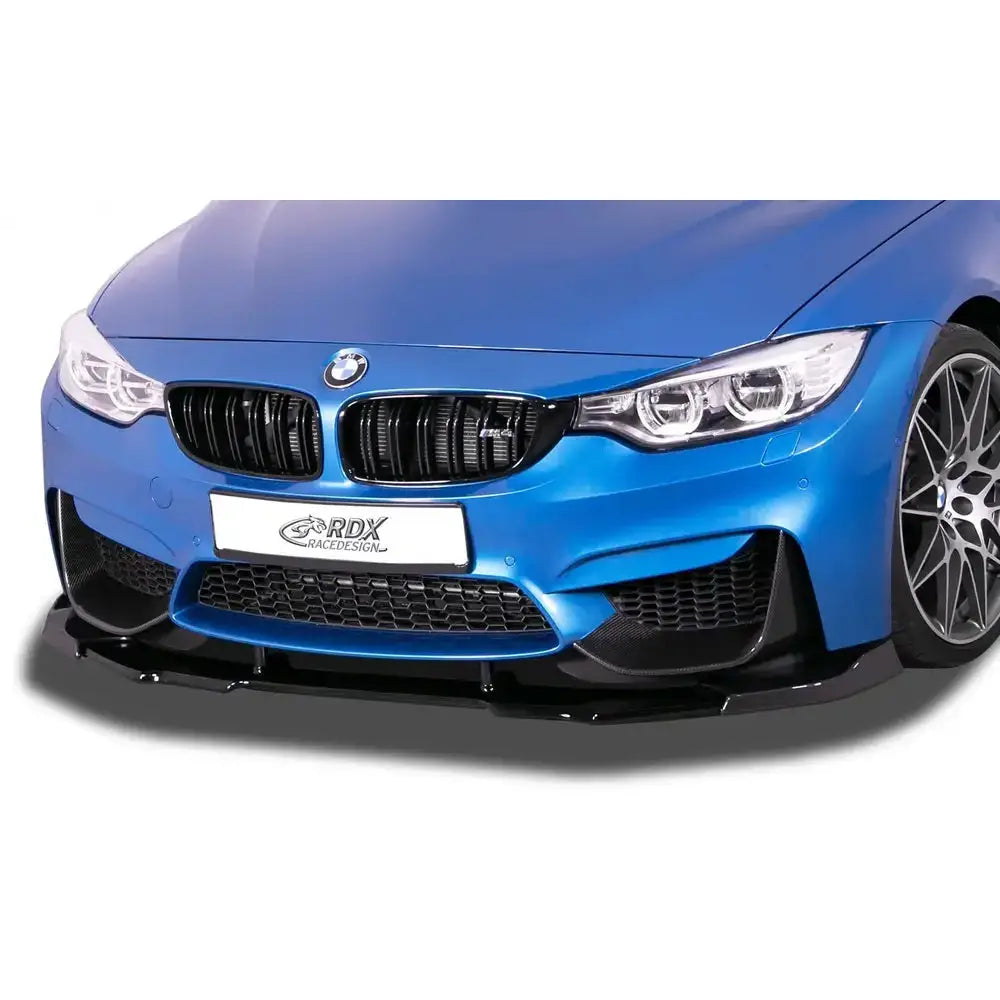 Frontspoiler BMW M4 F82 med sort plastleppe, blå bil, synlig grill, lykter og felger sett rett forfra.