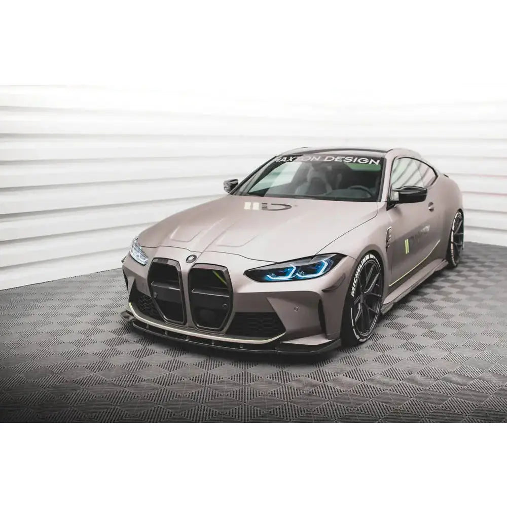 Front splitter på BMW M4 G82 med matt grå lakk, blå LED-lys og svart karbonspoiler sett forfra.