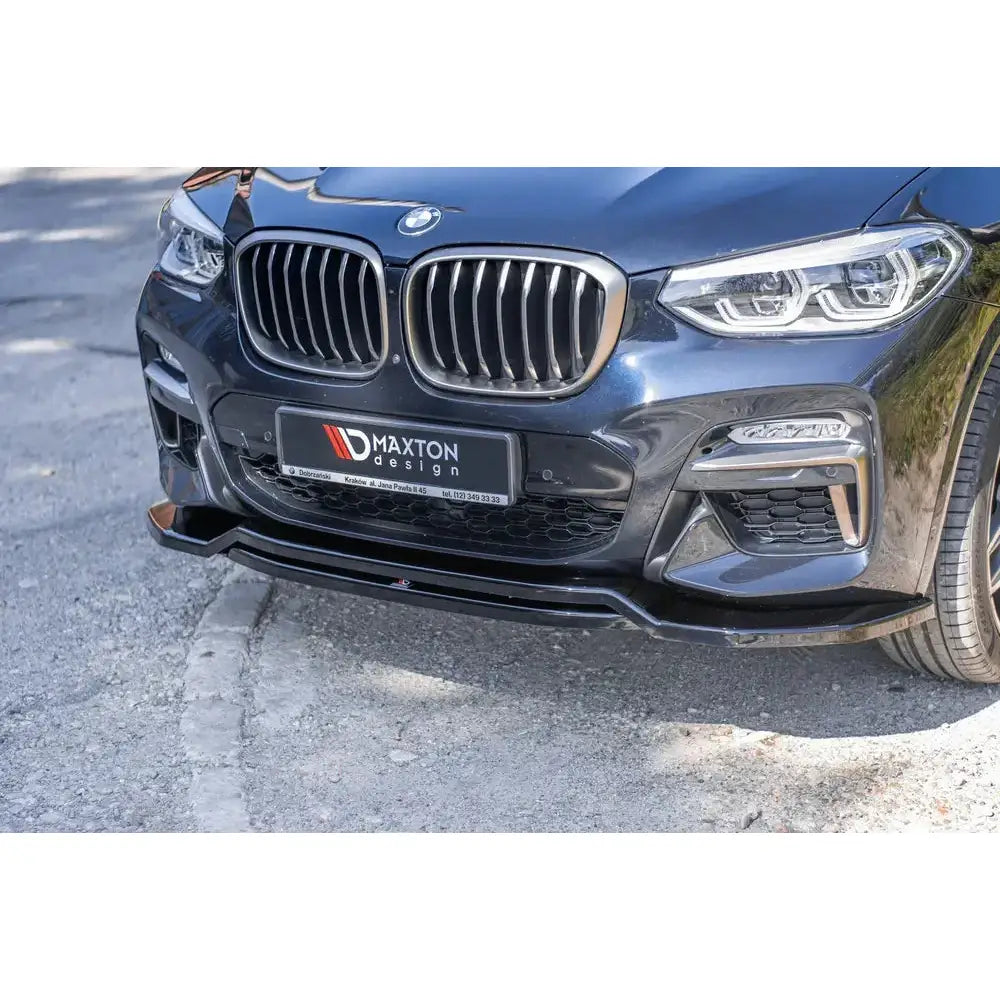 Front splitter på BMW X4 M-Pack G02 med sort spoiler, kromgrill og synlige detaljer foran i dagslys.