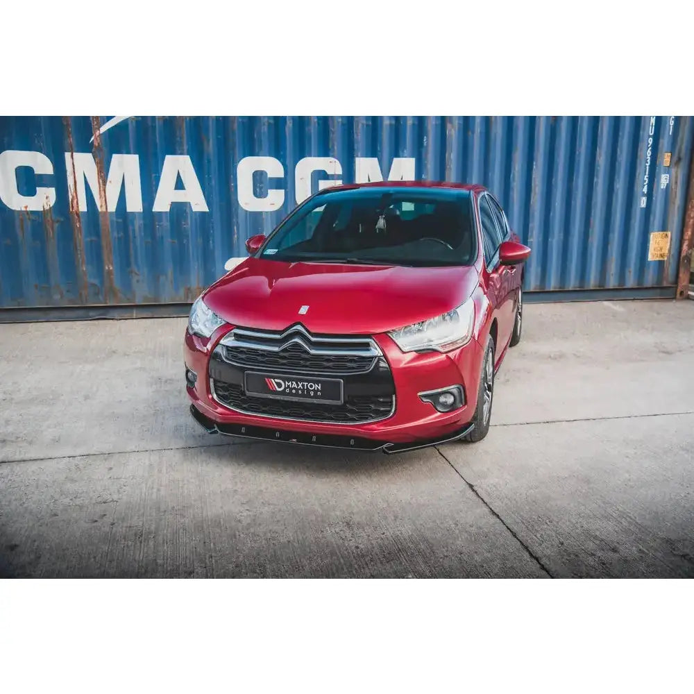 Frontleppe på Citroen DS4 montert foran, svart med kromdetalj, rød bil og blå container i bakgrunnen.