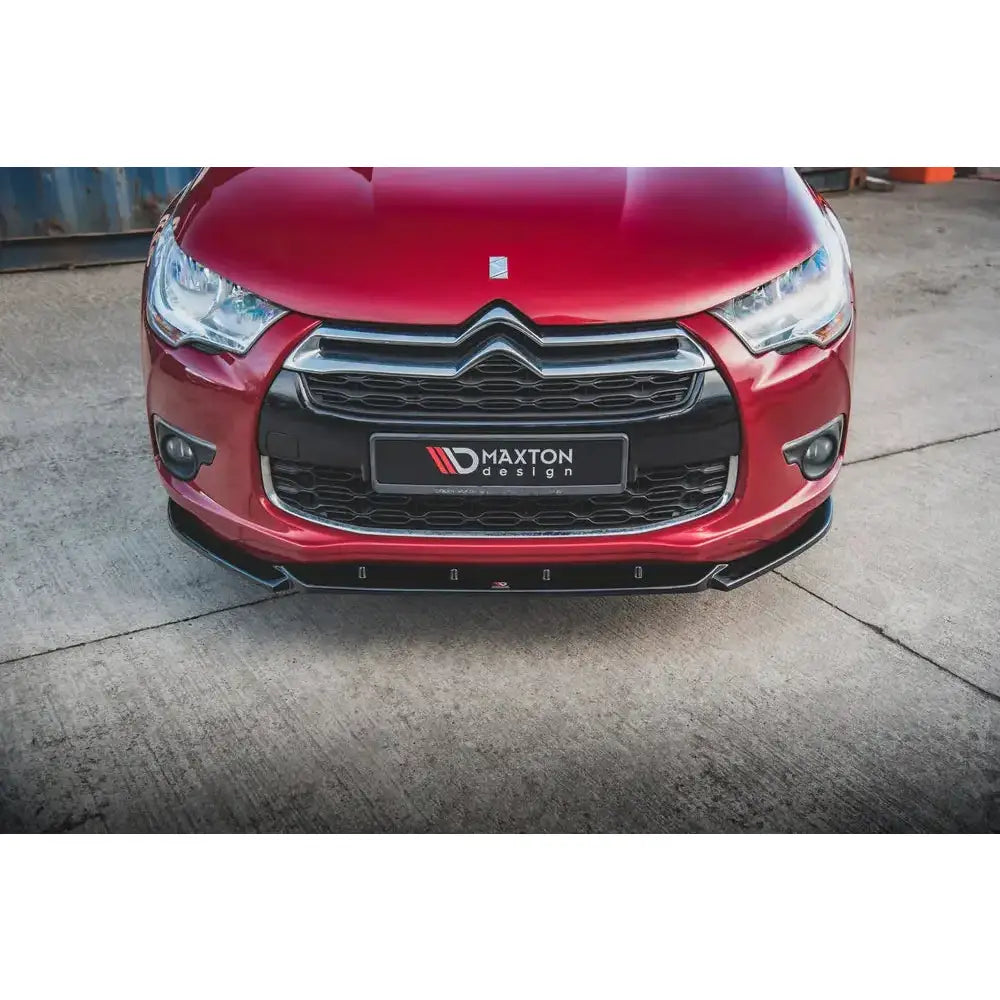 Spoiler på rød Citroen DS4 med sort grill og sort frontleppe sett forfra fra lav vinkel.