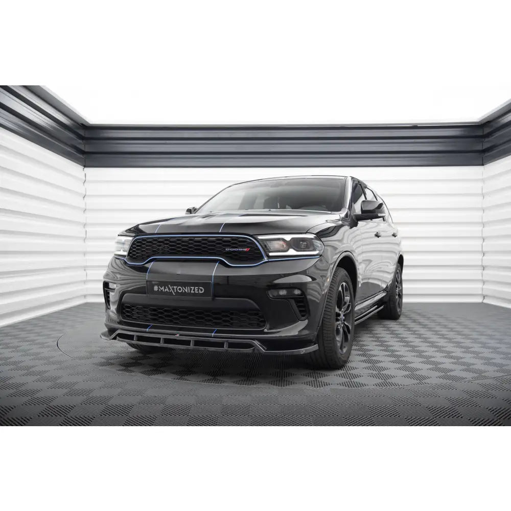 Spoiler på Dodge Durango Mk3 Facelift SUV med blå detaljer og mørke felger, sett forfra innendørs.