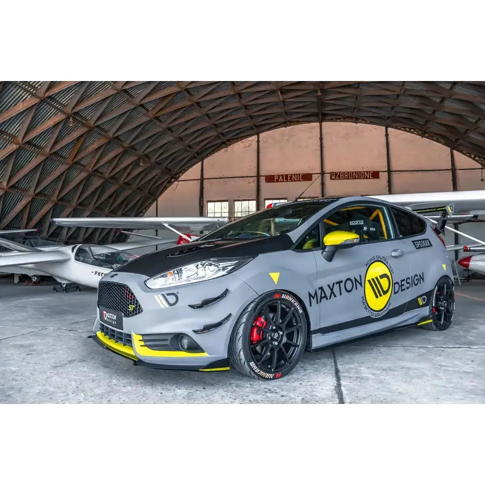 Frontleppe på Ford Fiesta 7 ST Facelift i grått og svart med gule detaljer, sett fra siden i hangar.