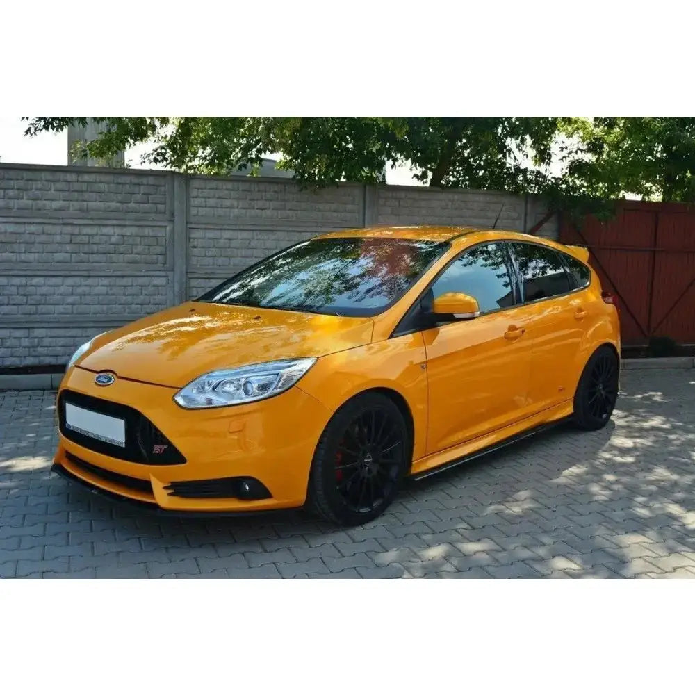 Front lip på gul-orange Ford Focus Mk3 ST med sorte felger, sett fra siden og litt forfra.