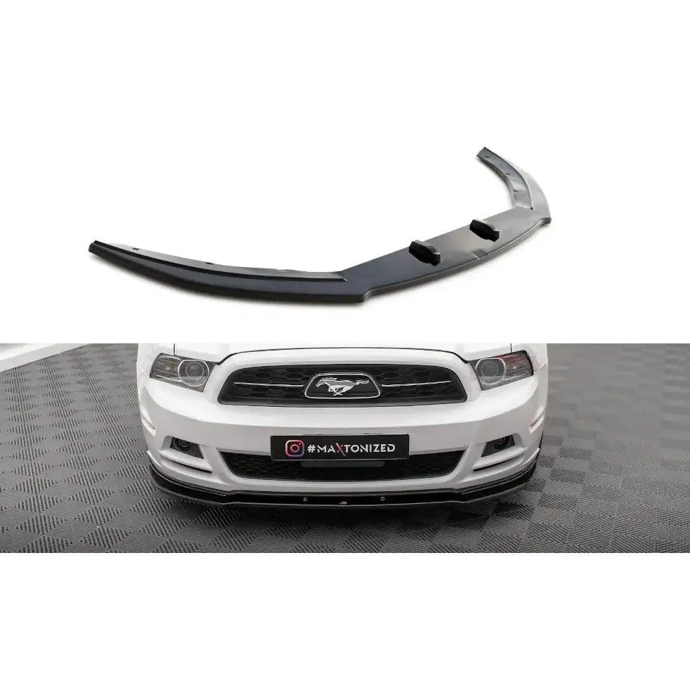 Frontspoiler til Ford Mustang Mk5 Facelift, svart plast montert på hvit bil sett forfra fra skrå vinkel.