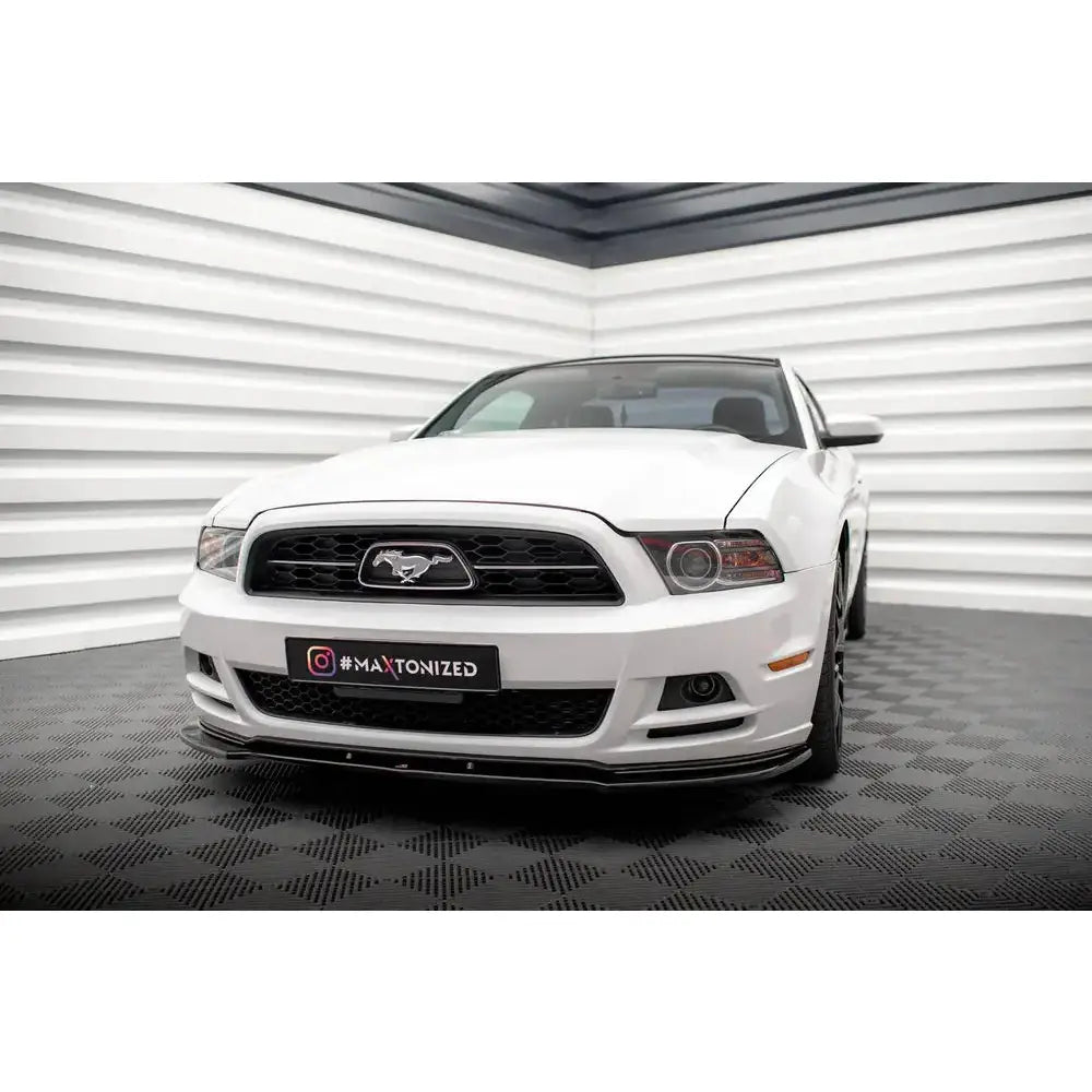 Front splitter på hvit Ford Mustang Mk5 Facelift parkert innendørs med sort grill og emblem.