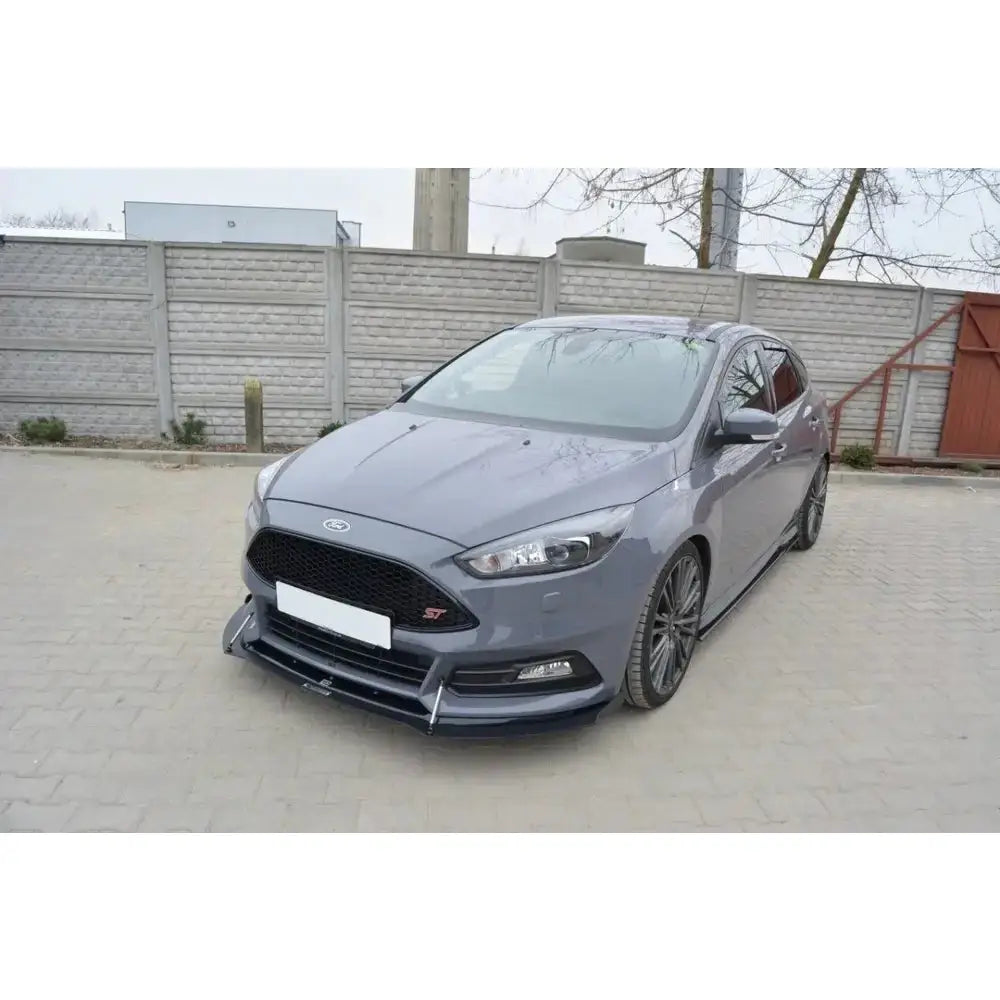 Front splitter på Ford Focus ST Mk3 Facelift med sporty design og svarte detaljer, parkert foran murvegg.