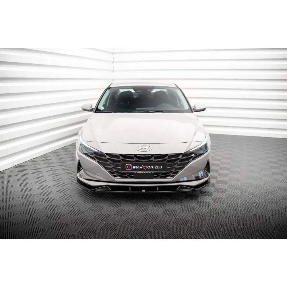 Frontleppe på Hyundai Elantra Mk7 vist forfra med sort grill og sølvfarget karosseri i lyst rom.