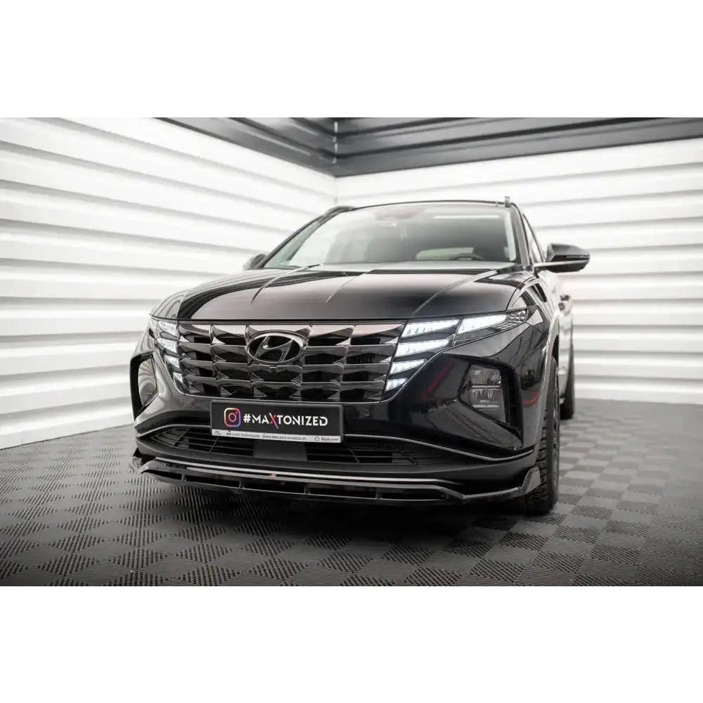 Spoiler på Hyundai Tucson 20- Mk4 V.2, svart SUV med markant grill og LED-lys, fotografert innendørs.