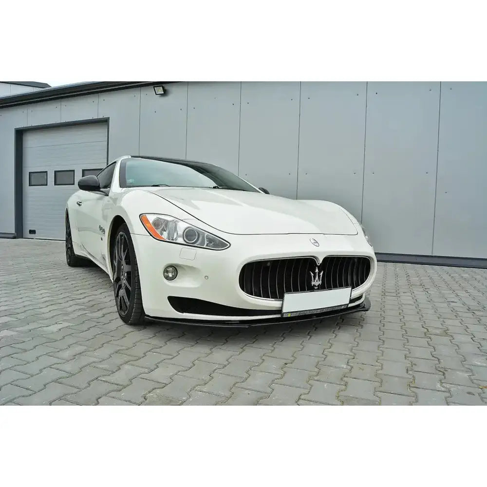 Frontleppe på Maserati Granturismo 2007-2011, hvit bil med sort grill parkert foran industribygg.