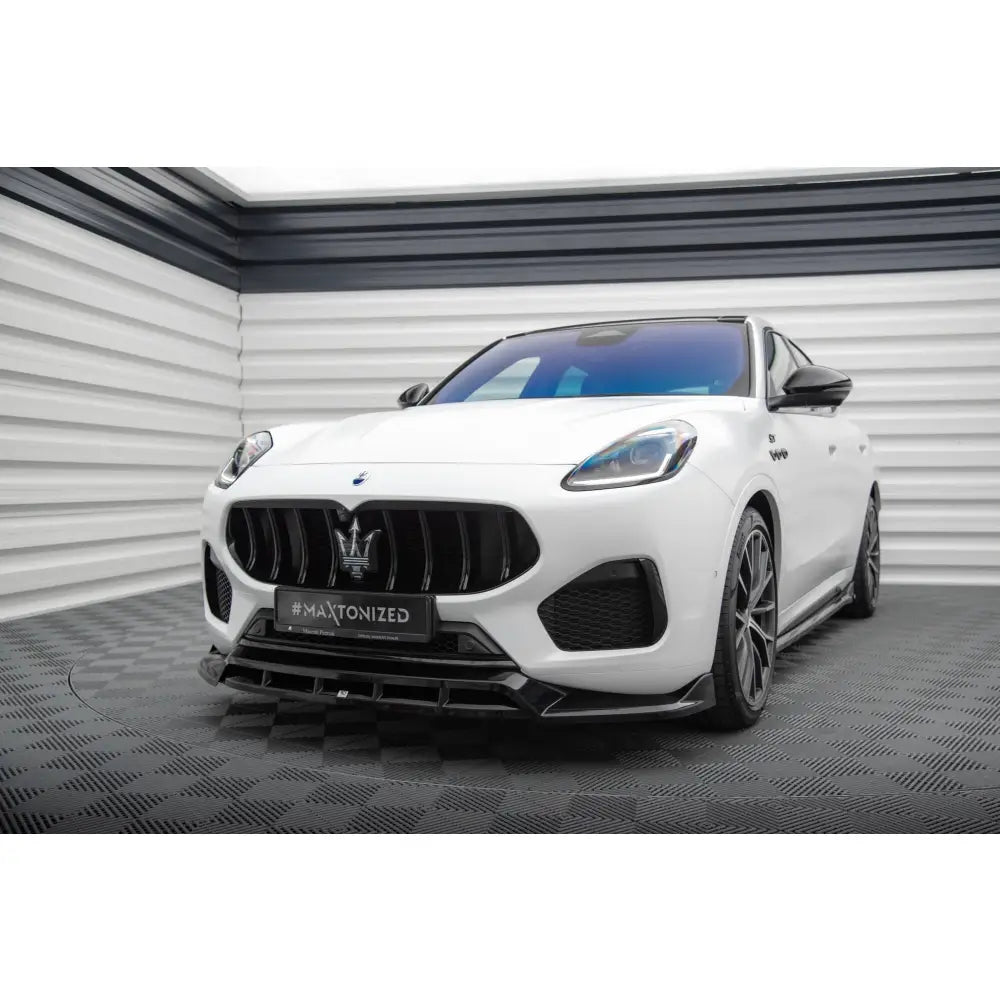 Frontleppe på Maserati Grecale GT med svarte detaljer, sett forfra i lyst rom på mønstret gulv.