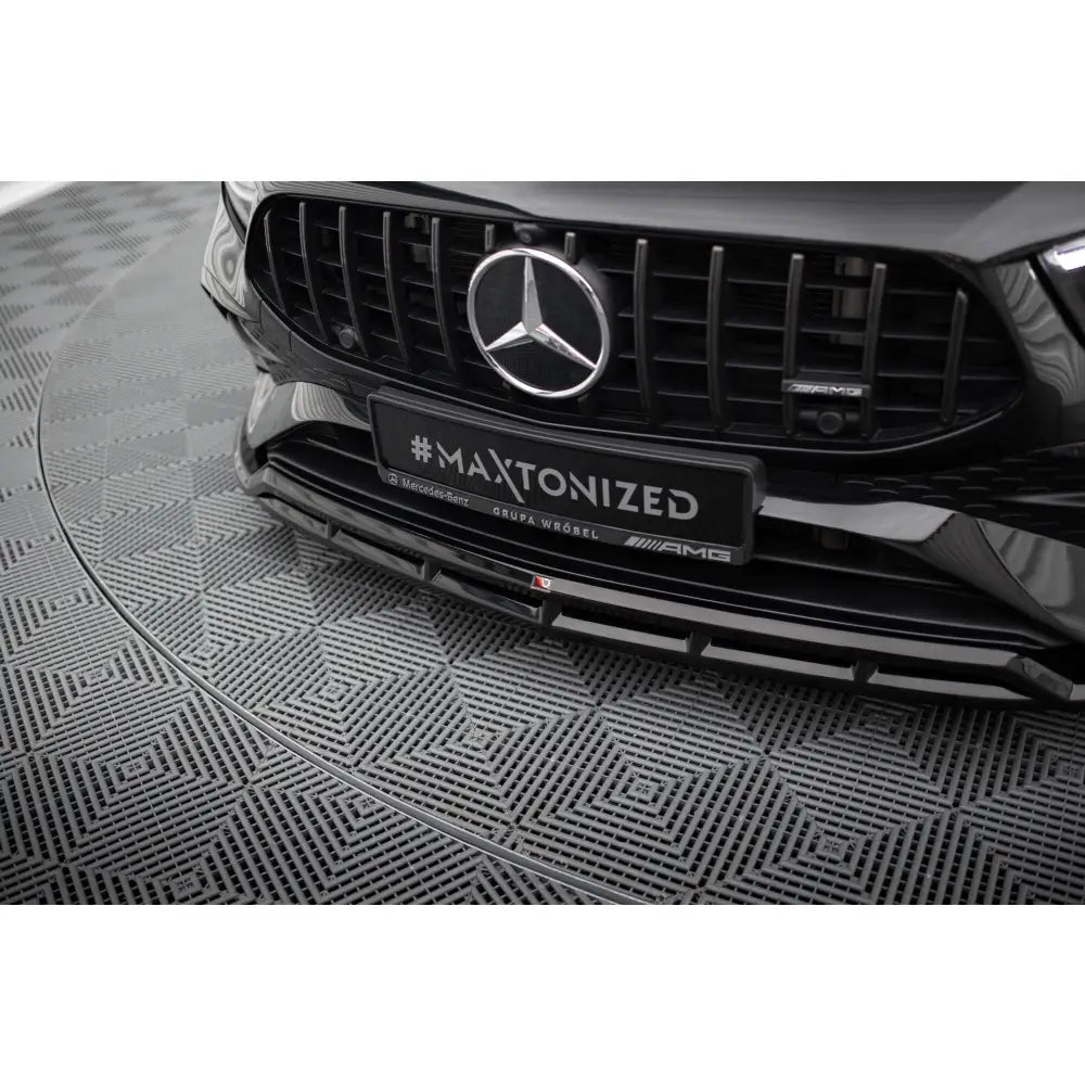 Spoiler til Mercedes A35 W177 Facelift i sort plast og metall, sett forfra med AMG-emblem og logo.