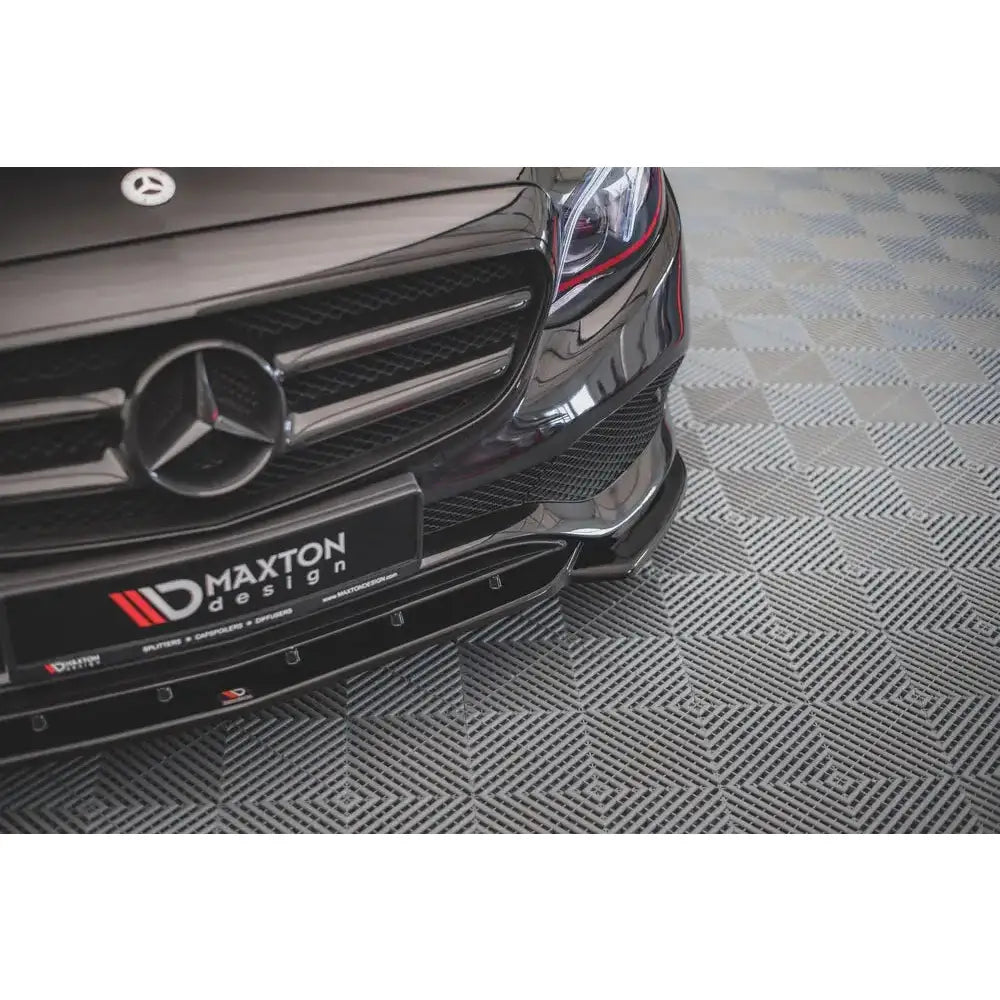 Front lip til Mercedes-Benz E W213, sort glanset spoiler med markerte kanter sett skrått forfra.