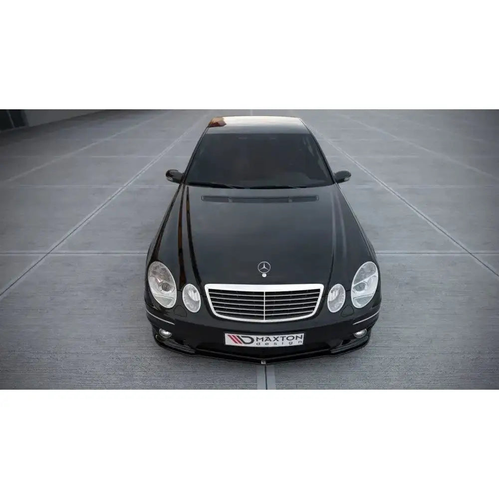 Frontspoiler på Mercedes E-Klasse W211 AMG Facelift, sort bil med sølvgrill sett ovenfra og forfra.