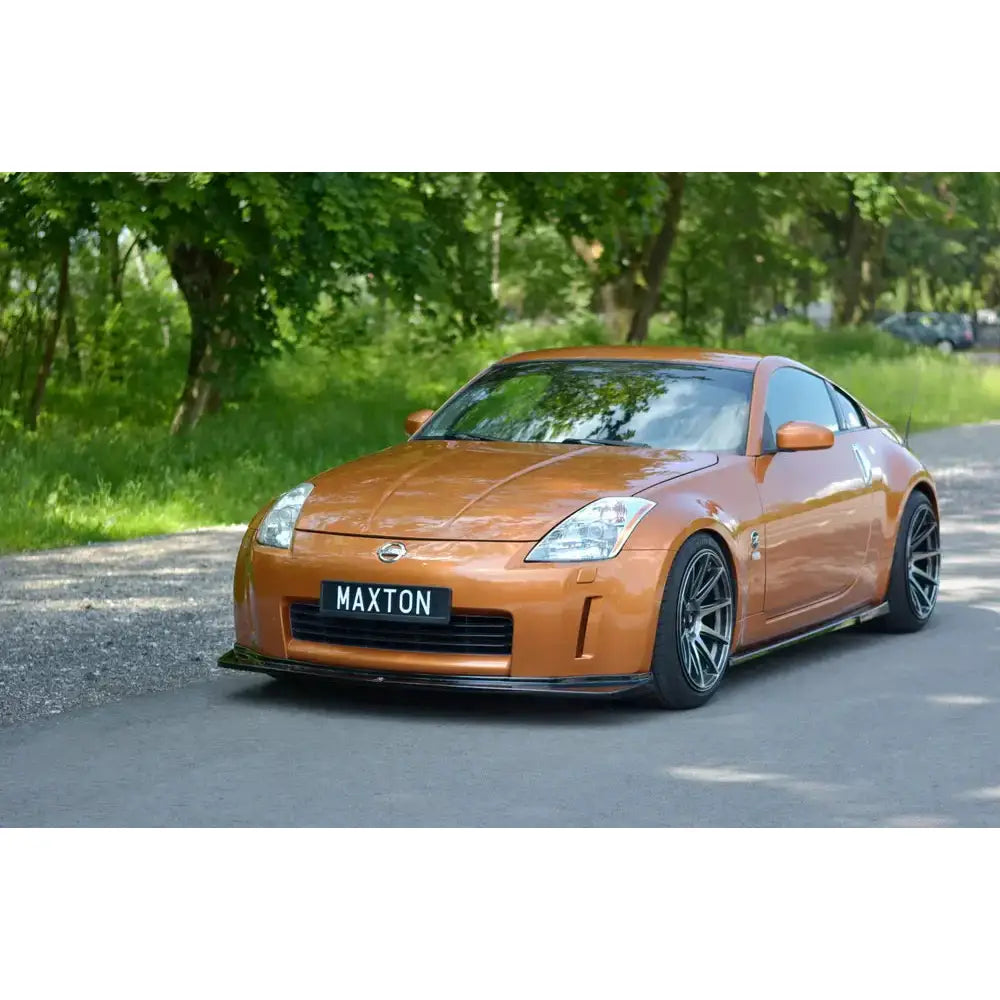 Frontleppe på oransje Nissan 350Z med svarte felger, sett skrått forfra, parkert foran grønn skog.