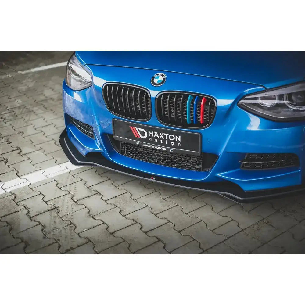 Spoiler Racing med flaps på blå BMW M135i F20, nærbilde av sort frontsplitter og grill med detaljer.