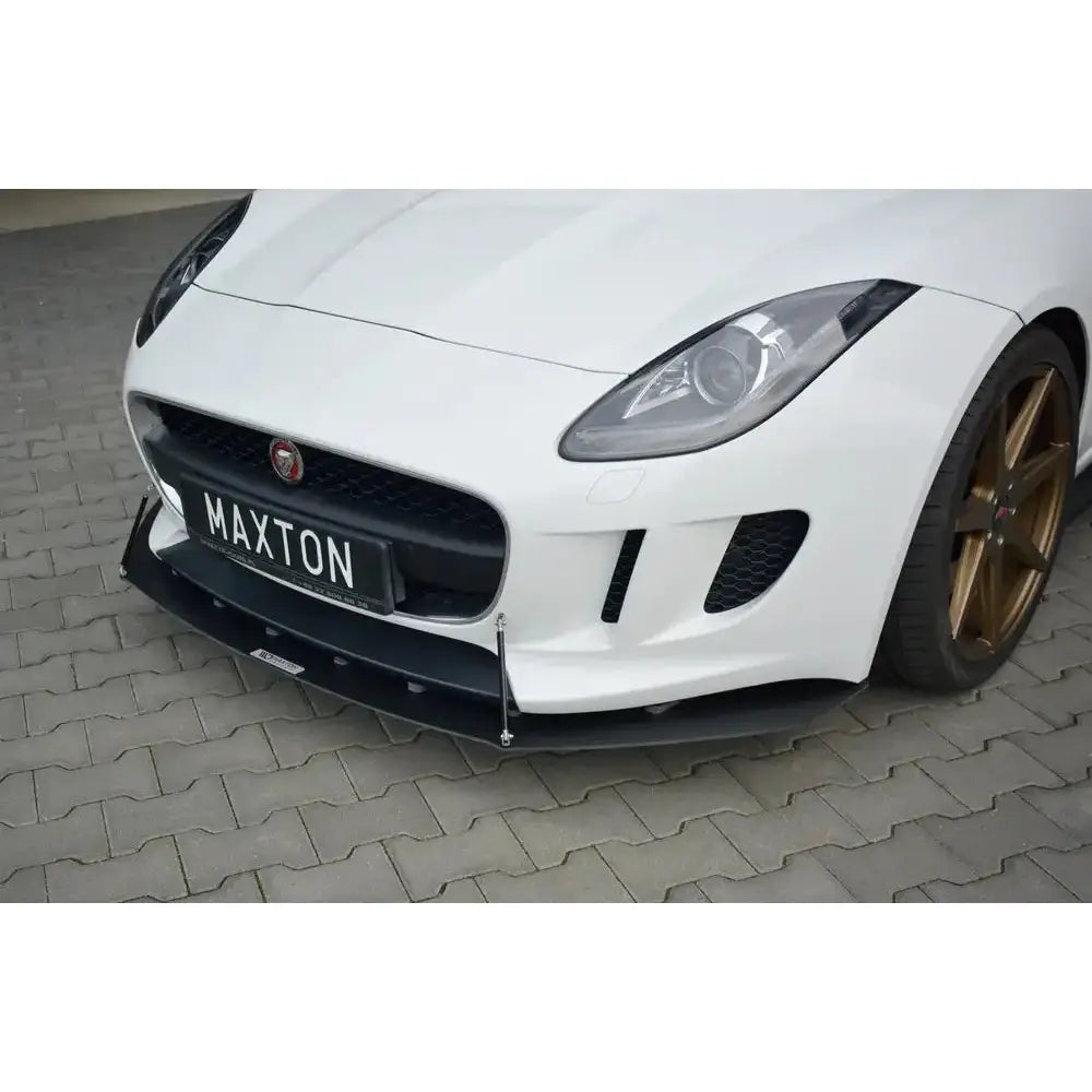 Front lip på Jaguar F-Type Racing med svart splitter, bronsefargede felger og metallstøtter, parkert ute.