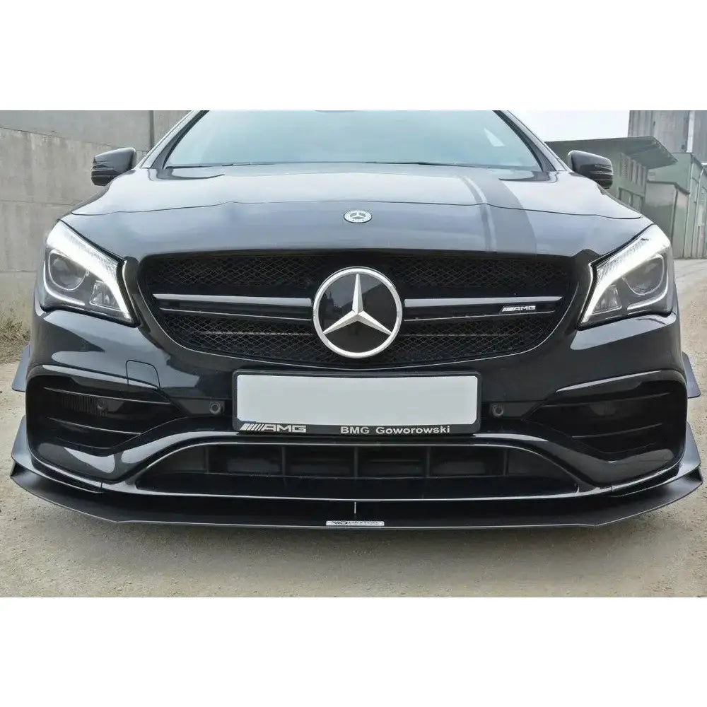 Spoiler på sort Mercedes Cla A45 AMG C117 Facelift med blank finish og sølvfarget emblem foran.