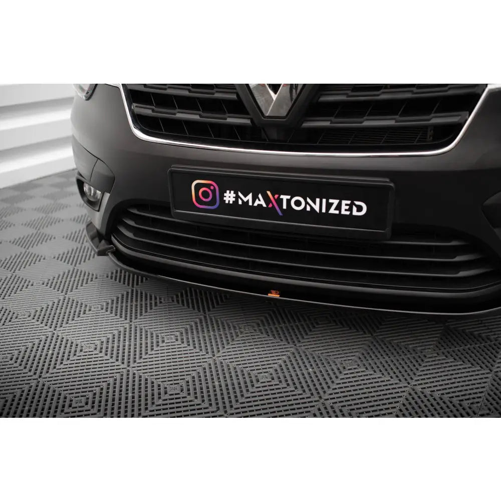 Spoiler på Renault Express Mk2, nærbilde av svart frontspoiler med grill mot grått mønstret gulv.