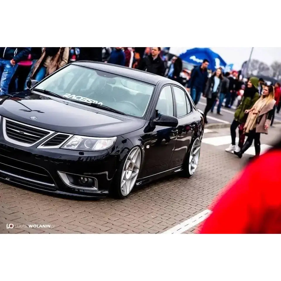 Front splitter på Saab 9-3 Turbo X, svart sedan senket med store sølvfelger parkert på gate.