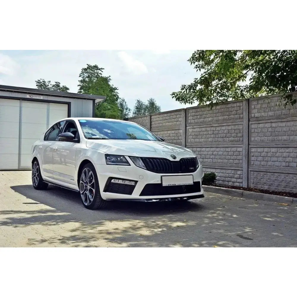 Frontspoiler på Skoda Octavia III RS med svarte felger, parkert utendørs ved murvegg.