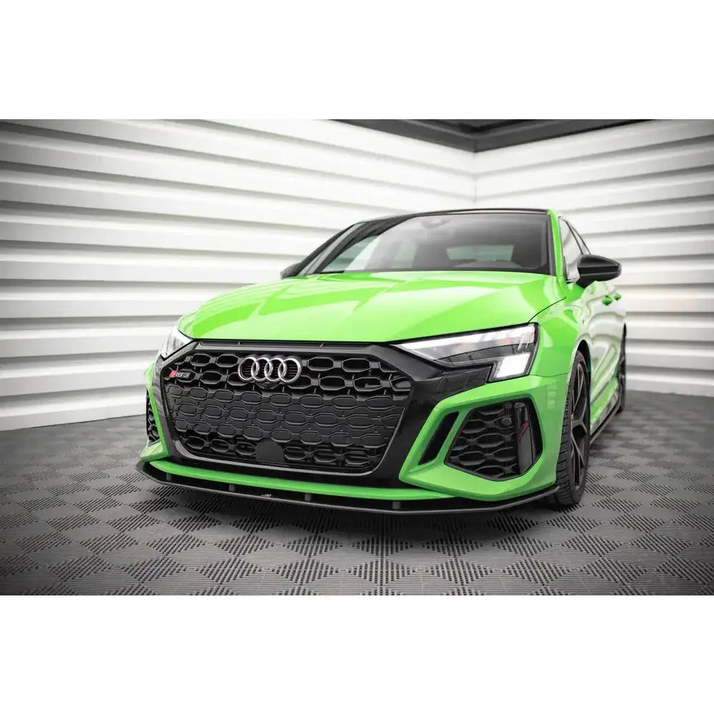 Front lip på Audi RS3 Sportback 8Y med sort grill og sportslige detaljer, sett skrått forfra innendørs.