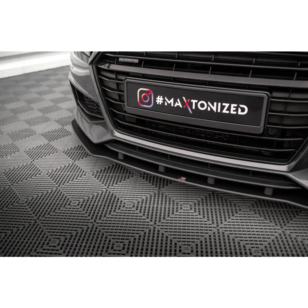 Front splitter på svart Audi TT S montert under støtfangeren, sett fra lav vinkel mot grått gulv.