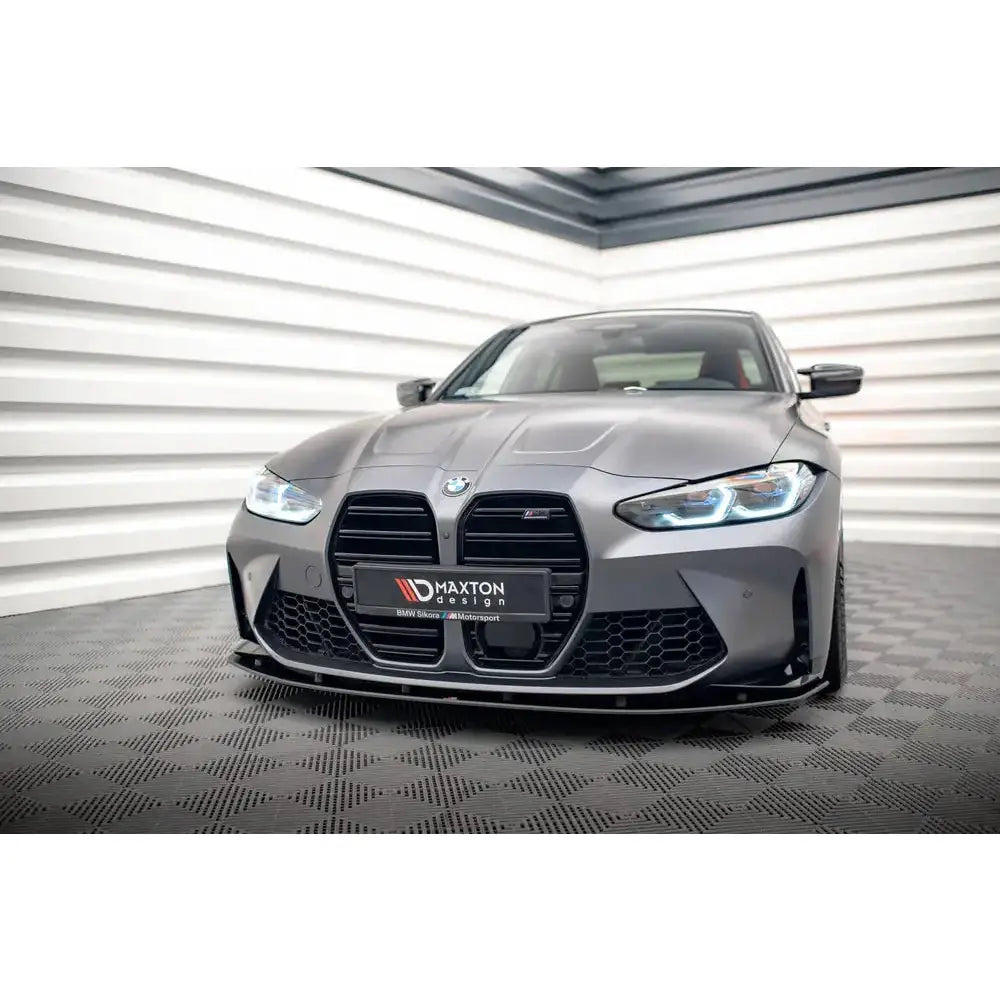 Front lip på BMW M4 G82 med karbon frontsplitter, svart grill og LED-lys i lyst moderne rom.