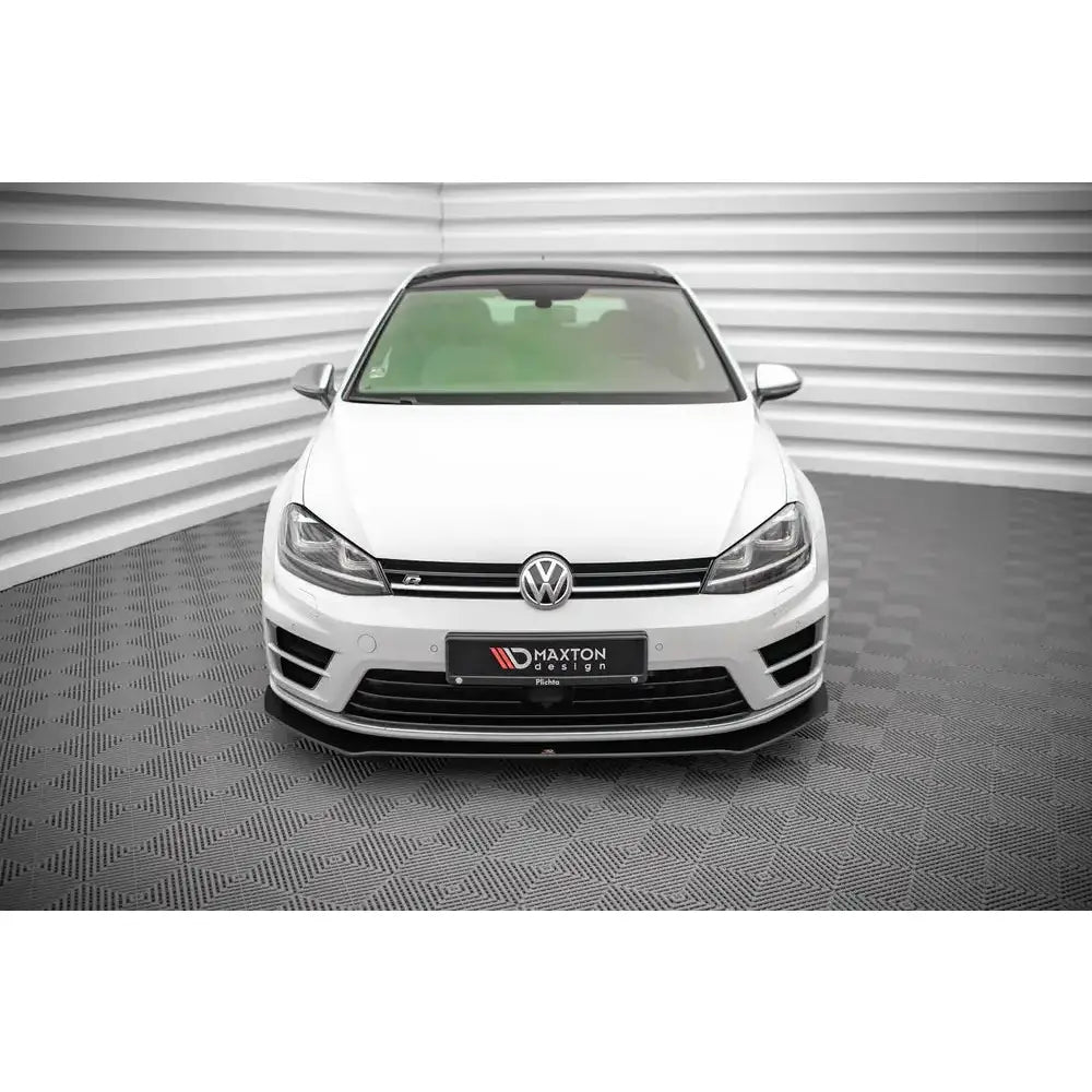 Frontspoiler på Volkswagen Golf R Mk7 med svarte detaljer, sett rett forfra i et lyst rom.
