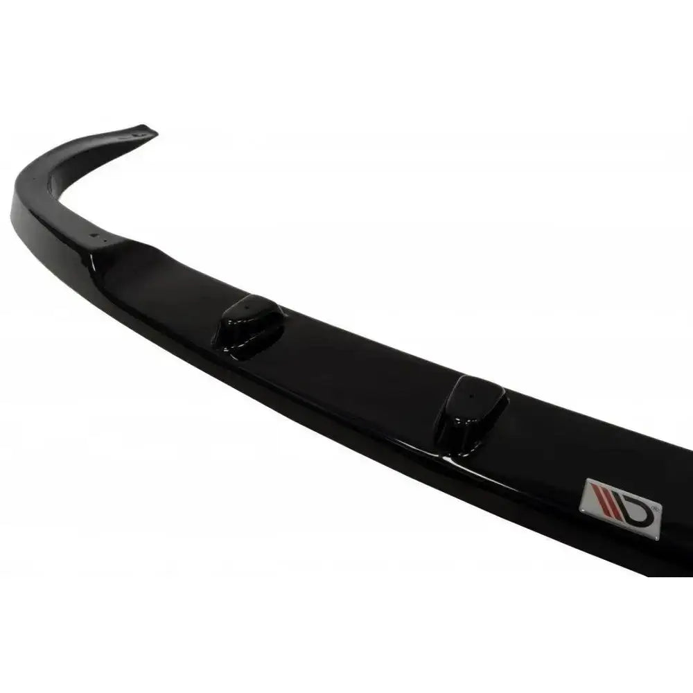 Front lip til Subaru Impreza GT, sort blank plast med tre forhøyninger og metall-logo, sett skrått.