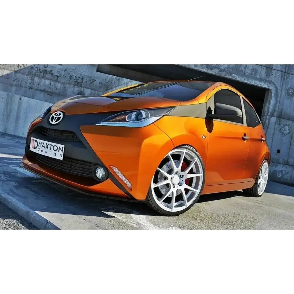Frontspoiler Toyota Aygo Mk2 i oransje med svarte detaljer, store hvite felger og moderne frontlykter.